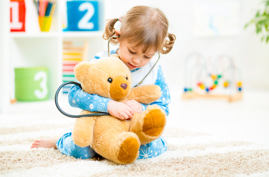 Niña pequeña con osito jugando a los médicos